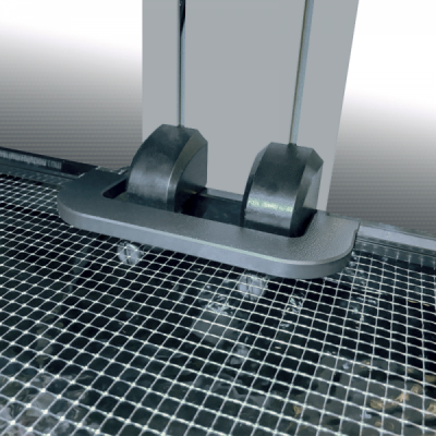 Ferramenta metálica com duas roldanas pretas e haste prateada numa grelha metálica