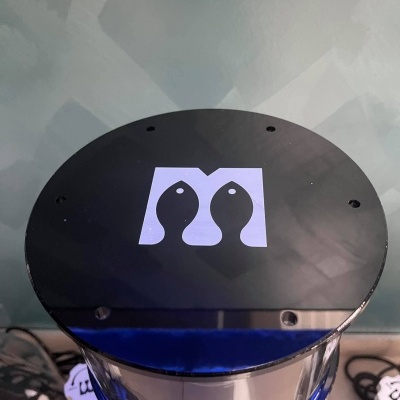 Dispensador cilíndrico transparente com tampa preta e logotipo de peixes em branco