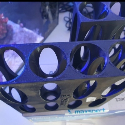 Suporte preto em plástico com orifícios circulares sobre caixa Maxspect