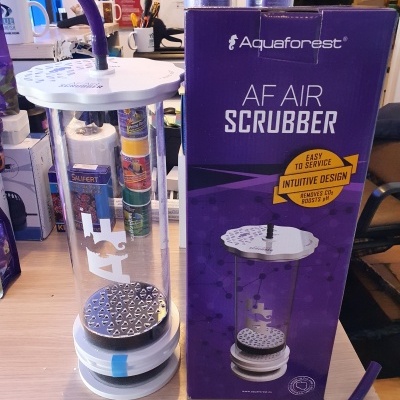 Dispositivo cylindrical transparente com base e topo brancos, tubo roxo conectado no topo, ao lado da caixa roxa da marca Aquaforest com texto AF AIR SCRUBBER