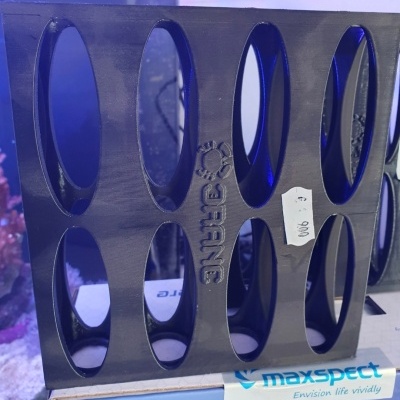 Suporte preto Maxspect Bio-Sphere com várias aberturas ovais em plástico sobre embalagem azul