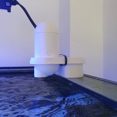 Dispositivo branco junto à borda de um aquário com água