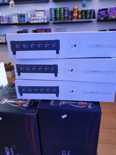 Caixas brancas de ventiladores Ocean Breeze empilhadas sobre caixas negras numa loja
