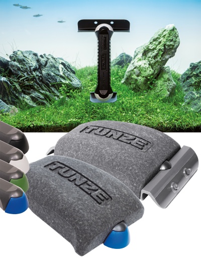 Dois dispositivos eletrónicos cinzentos com o texto TUNZE e acessórios coloridos junto a um aquário com rochas