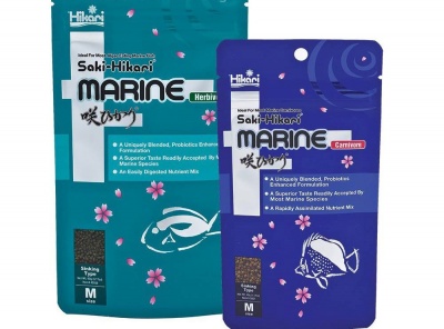 Dois pacotes de alimento para peixes Saki-Hikari Marine, um verde com flores e outro azul com peixe desenhado