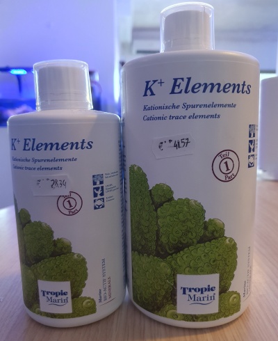 Duas garrafas brancas do produto K+ Elements com ilustração de algas verdes e texto em alemão e inglês.