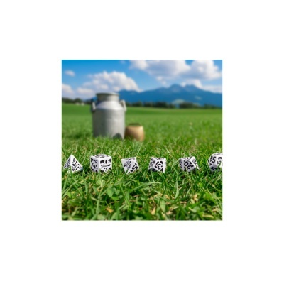 Dados brancos com números e desenhos de vacas sobre relva verde e recipiente metálico ao fundo