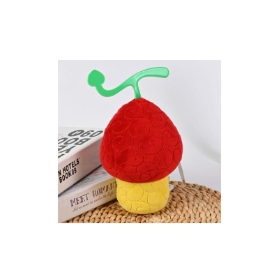 Brinquedo artesanal em forma de cogumelo vermelho e amarelo com haste verde em superfície de palha com livros ao lado