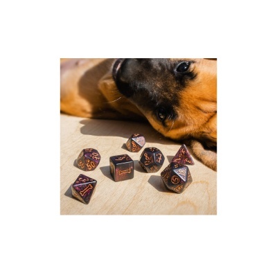 Dados poliédricos escuros com números laranja e símbolos, com cabeça de cão castanho ao fundo