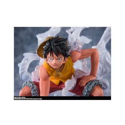 Figura de ação de personagem anime com chapéu de palha e colete amarelo em fundo desfocado