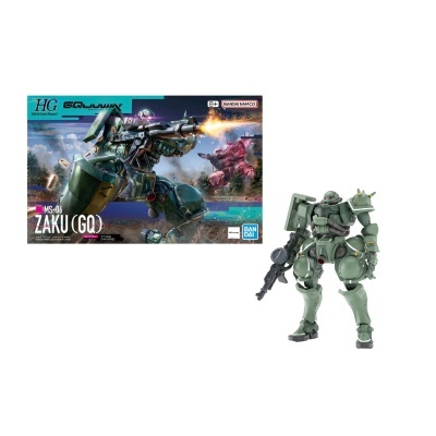 Modelo de robô ZAKU (GQ) verde com armas e caixa ilustrada com robôs de combate em ação.