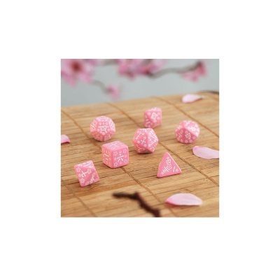 Dados cor-de-rosa com símbolos brancos sobre tapete de bambu com pétalas cor-de-rosa