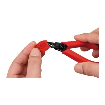 Mãos a segurar alicate vermelho e preto a cortar objeto vermelho com números