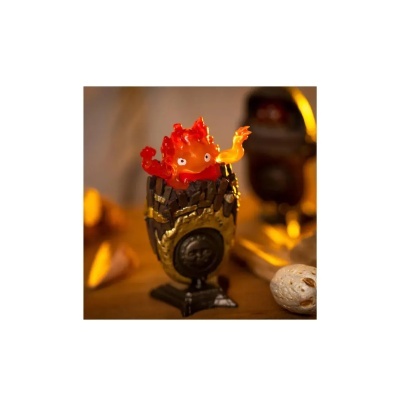 Figura decorativa de chama vermelha e laranja com olhos numa base dourada e preta