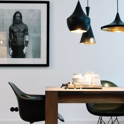 Sala de jantar moderna com mesa de madeira, cadeiras pretas, candeeiros suspensos negros e fotografia em preto e branco na parede