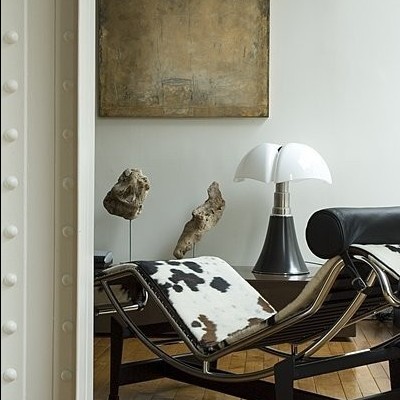 Chaise longue com estofado em pele de vaca e lâmpada numa mesa ao lado