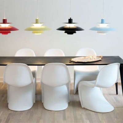 Sala de jantar com mesa preta, cadeiras brancas e candeeiros coloridos suspensos