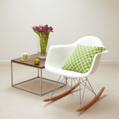 Cadeira de baloiço branca com almofada verde e mesa de apoio com flores e caneca