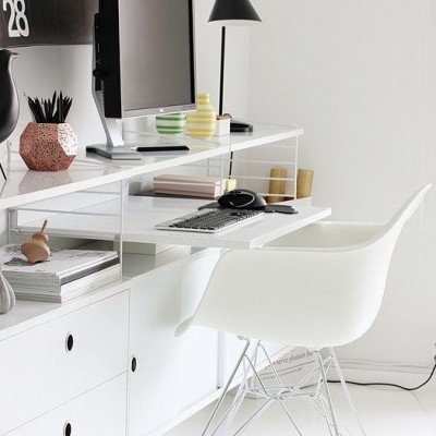 Área de trabalho branca com secretária, cadeira, monitor, candeeiro e calendário a preto e branco