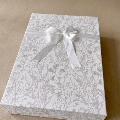 Caixa de presente branca com padrão floral cinzento e laço branco