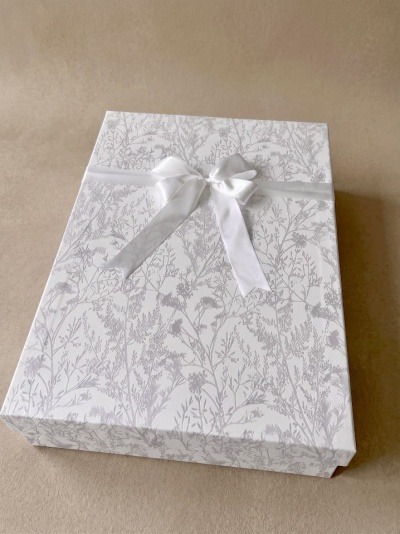 Caixa de presente branca com padrão floral cinzento e laço branco