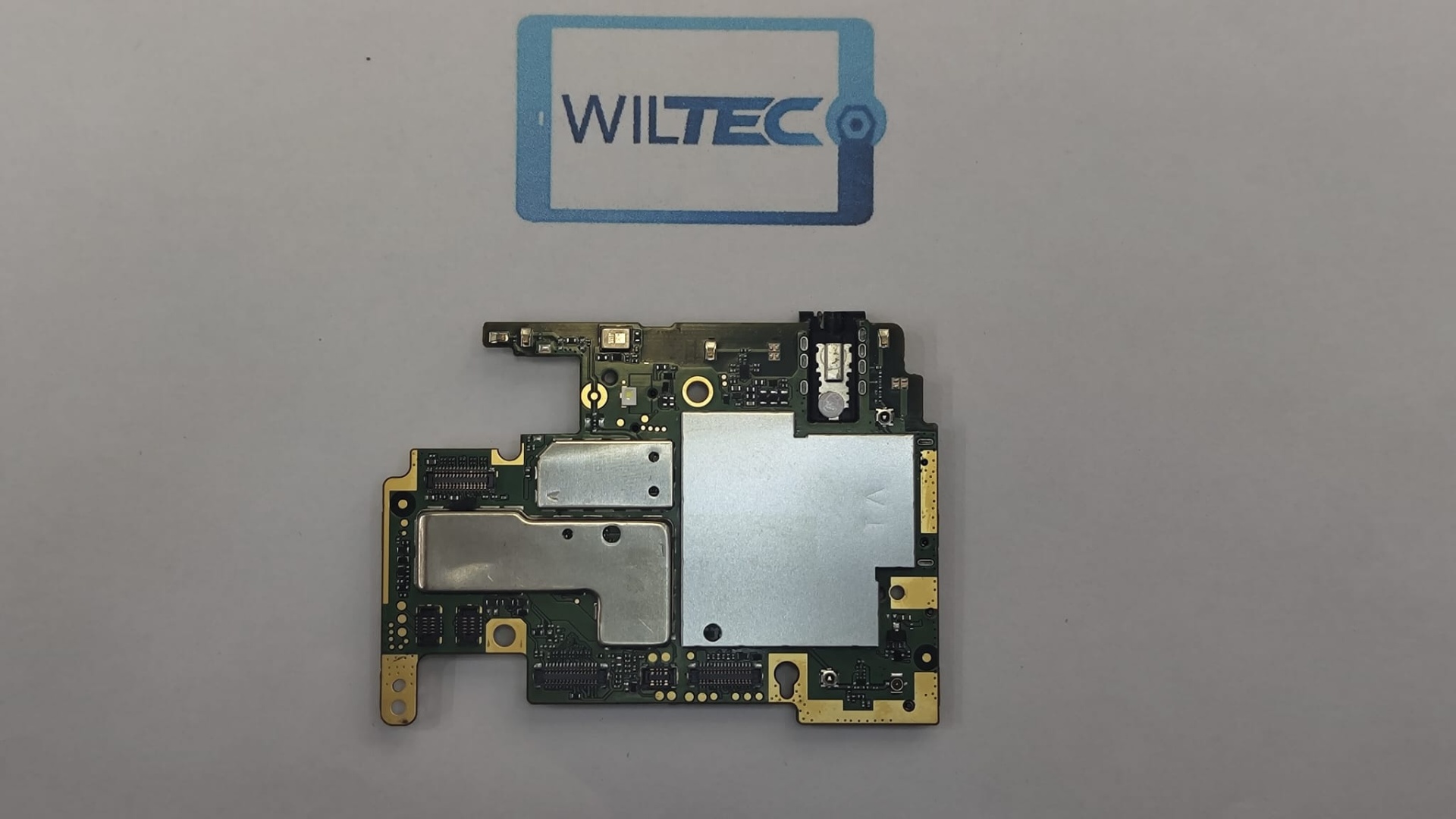 Motherboard Xiaomi Redmi 6 – 32GB – Testada e Desbloqueada Placa eletrónica de circuito impresso sobre fundo com logótipo WILTEC