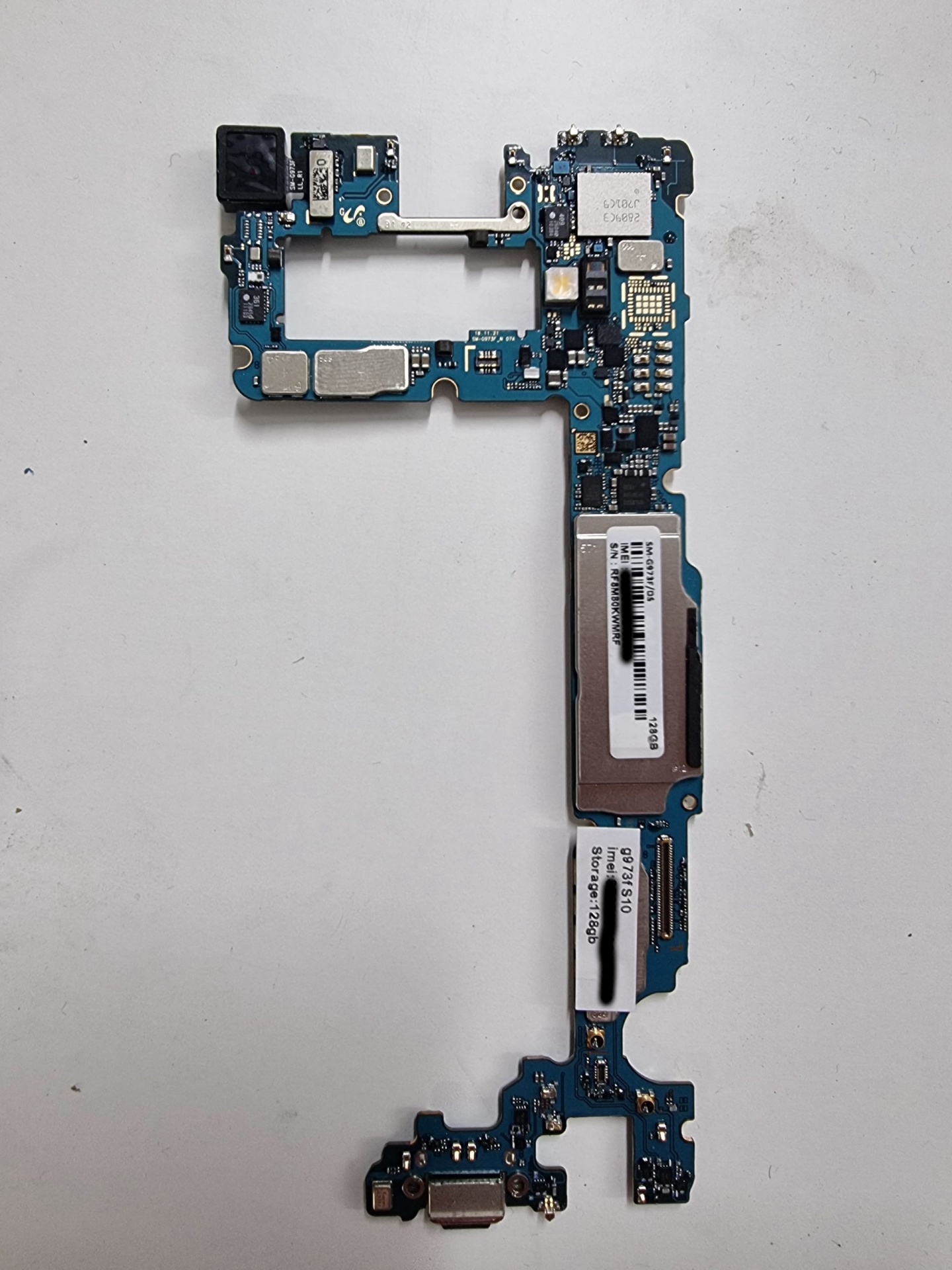 Motherboard Samsung Galaxy S10 (SM-G973F) – 128GB – Testada e Desbloqueada Placa mãe azul para dispositivo móvel com componentes e etiquetas
