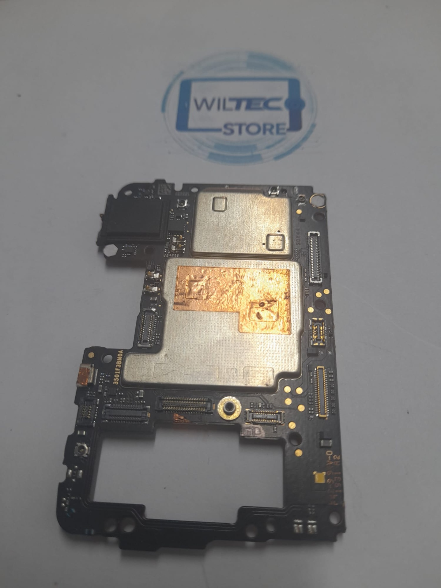 Motherboard Xiaomi Mi 9 Lite – 128GB – Desbloqueada – Testada Placa eletrónica com componentes e superfície metálica sobre fundo com logotipo WILTEC STORE