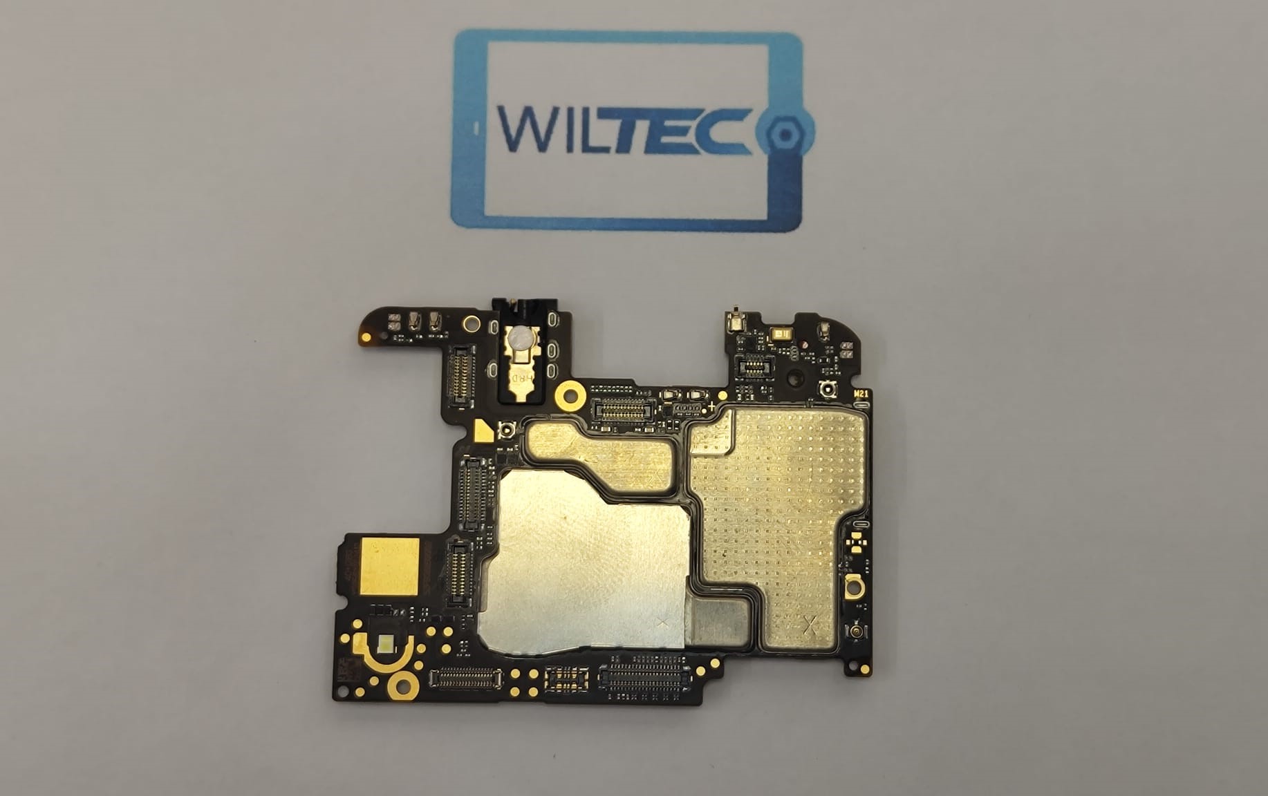 Motherboard Xiaomi Mi A3 – 128GB – Testada e Desbloqueada Placa eletrónica preta com componentes metálicos sobre fundo branco com logo WILTEC