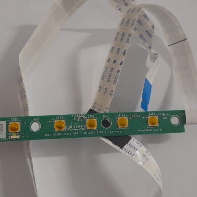 Placa eletrónica verde com botões amarelos e cabos planos brancos.