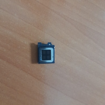 Componente eletrónico pequeno preto e cinza sobre superfície de madeira