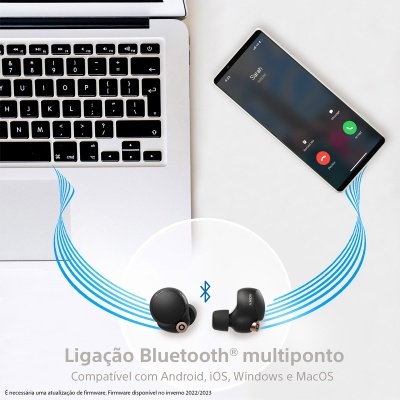 Auriculares Bluetooth pretos próximos de laptop e smartphone com chamada ativa