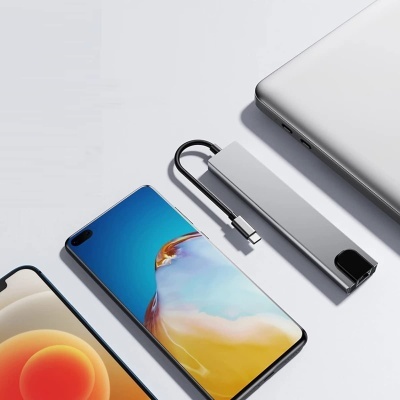 Adaptador USB-C cinza prateado entre laptop e dois telemóveis