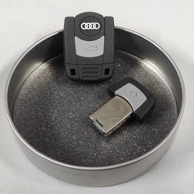 Dispositivos USB parecidos com chaves Audi dentro de uma bandeja metálica redonda.