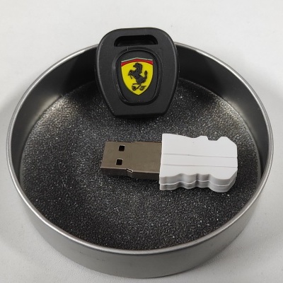 Pen USB Ferrari preto com símbolo colorido numa caixa metálica redonda.