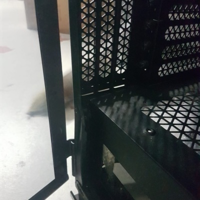 Interior de caixa de computador preto com padrões de ventilação triangulares em metal.