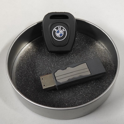 Pen USB preto e cinza com capa BMW dentro de caixa metálica redonda