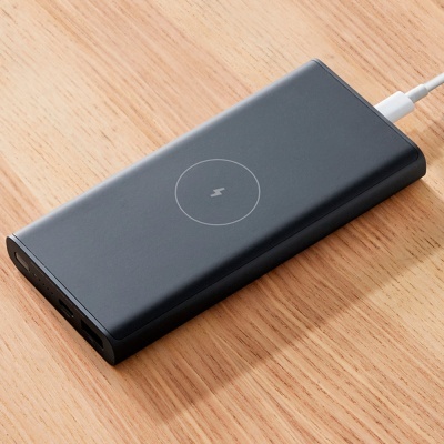 Carregador portátil preto com símbolo de raio no centro sobre madeira clara