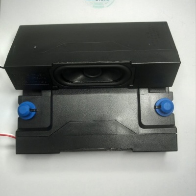 Coluna de som preta vista de cima com botões azuis e logo WILTEC STORE ao fundo