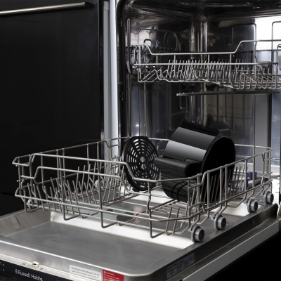 Máquina de lavar loiça aberta com utensílios pretos na prateleira metálica