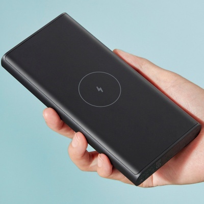 Power bank preto com símbolo de carregamento sem fios circular no centro, segurado por uma mão