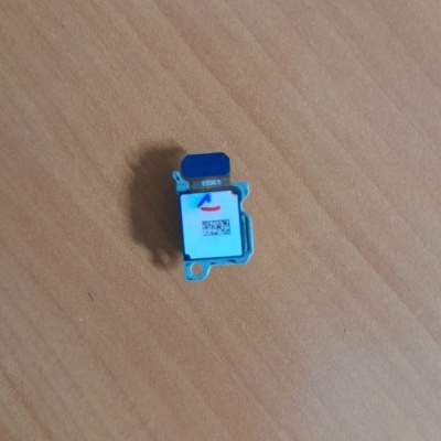 Componente eletrónico azul e branco com etiqueta e QR code sobre madeira clara