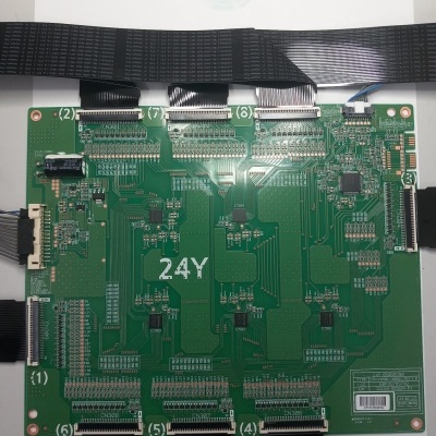 Placa eletrónica verde com circuitos e conectores de fita preta com etiqueta e código de barras.