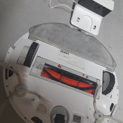 Aspirador robô branco com escovas e suporte de carregamento