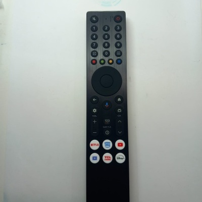 Comando remoto preto com botões coloridos, numéricos e botões de plataformas de streaming em fundo branco.