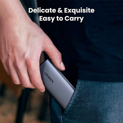 Dispositivo cinza com texto UGREEN sendo colocado em bolso de calça azul.