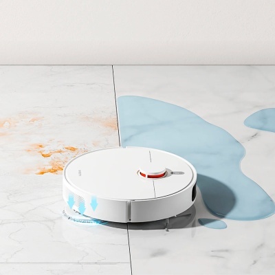 Robô aspirador branco a limpar chão com manchas e líquidos