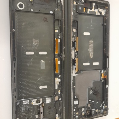 Duas carcaças traseiras de telemóveis desmantelados com componentes internos visíveis