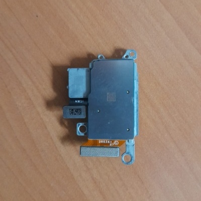 Componente eletrónico metálico com conectores e cabo flexível sobre mesa de madeira