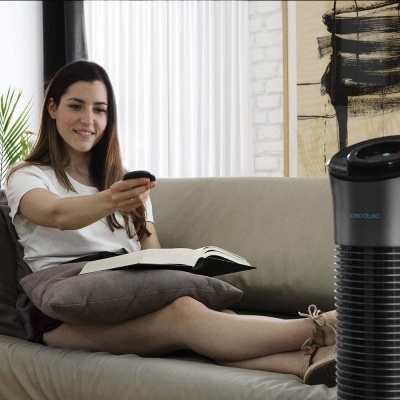 Aparelho de ar condicionado portátil Cecotec preto e cinza em frente a mulher num sofá cinza